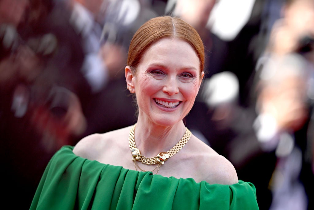 Actress Julianne Moore smiles in an off-the-shoulder green dress wearing a gold neckless and her hair back.