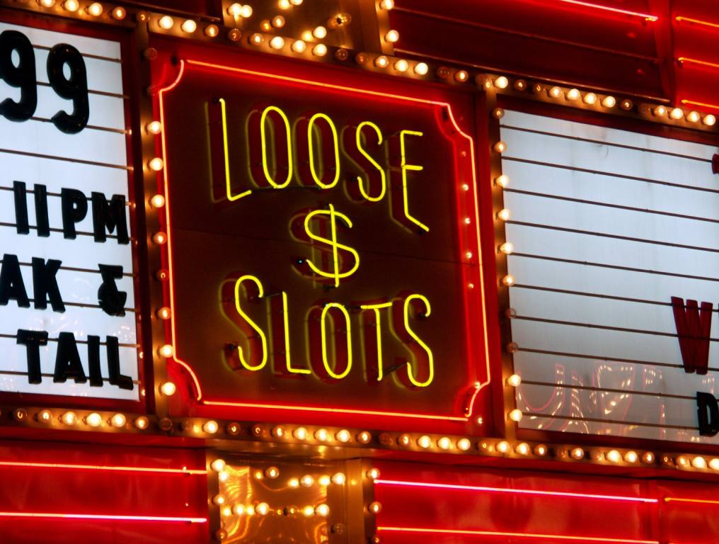 A "loose slots" sign on a marquee is illuminated in gold letters with a dollar sign in the middle. It is surrounded by a red border and gold lights. Many casinos in Las Vegas try to draw players in with similar marketing.