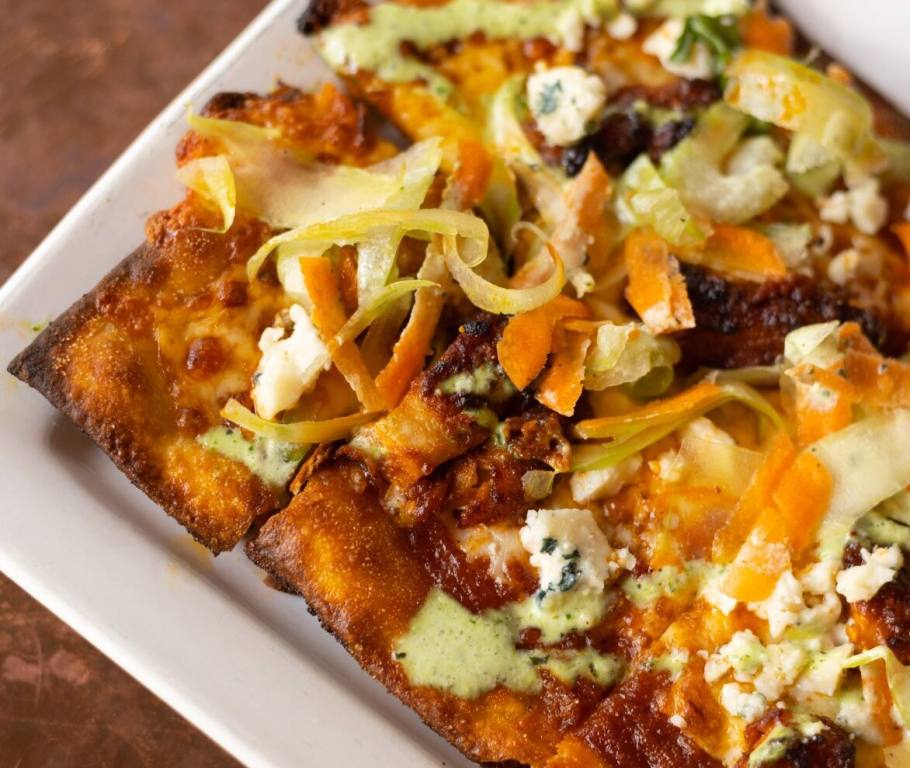 A plate of buffalo chicken flatbread pizza sits on a white plate. One of the menu items at Flight Club Las Vegas.