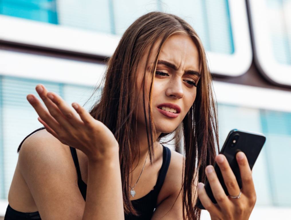 Bad News. Young woman checking the messages and post on her mobile phone. Shocked by reading the bad news on her smart phone. Urban Young Generation Social Media Lifestyle Portrait.