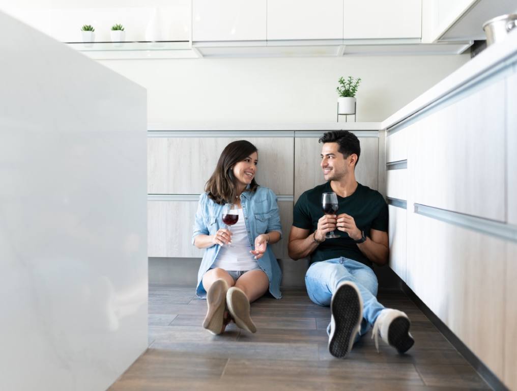 A couple sitting on the floor talking over a bottle of wine