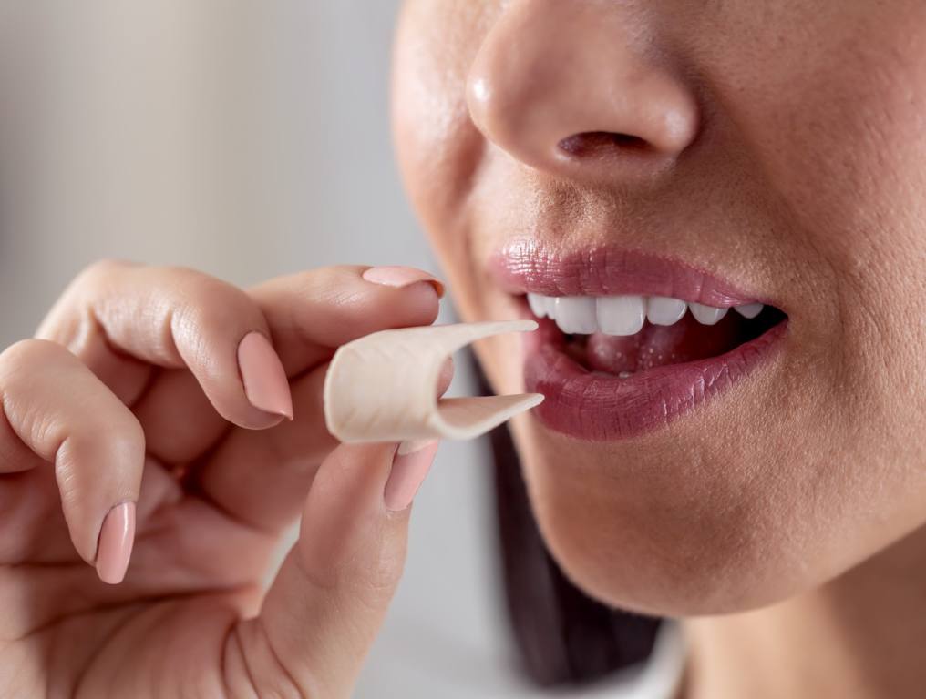 A woman putting a piece of gum in her mouth