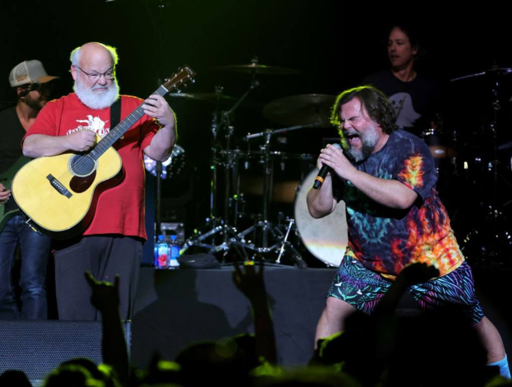 Actors/recording artists Kyle Gass (L) and Jack Black (R) of Tenacious D perform at The Theater at Virgin Hotels Las Vegas on December 30, 2022 in Las Vegas, Nevada. Kyle is wearing a red shirt and playing guitar while Jack is in a button up shirt with flames on it.