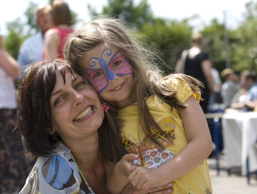 Mother and Face Painted Daughter cuddle at an arts fair. One of many activities that will be available at the Las Vegas events through the Las Vegas-Clark County Library District.