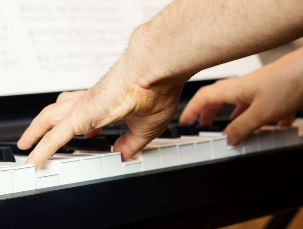 Hands on the keys of a piano ready to play a song