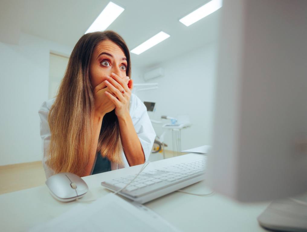 Puzzled shocked general practitioner looking at her computer