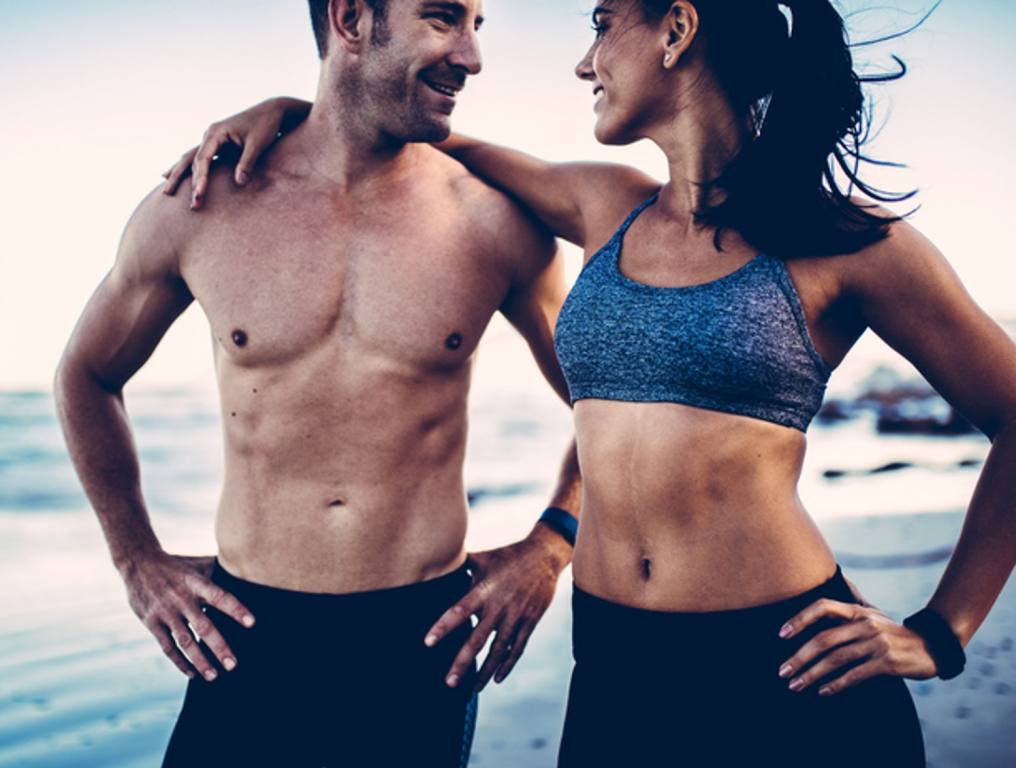 Close-up of young adult's muscular bodies on the beach