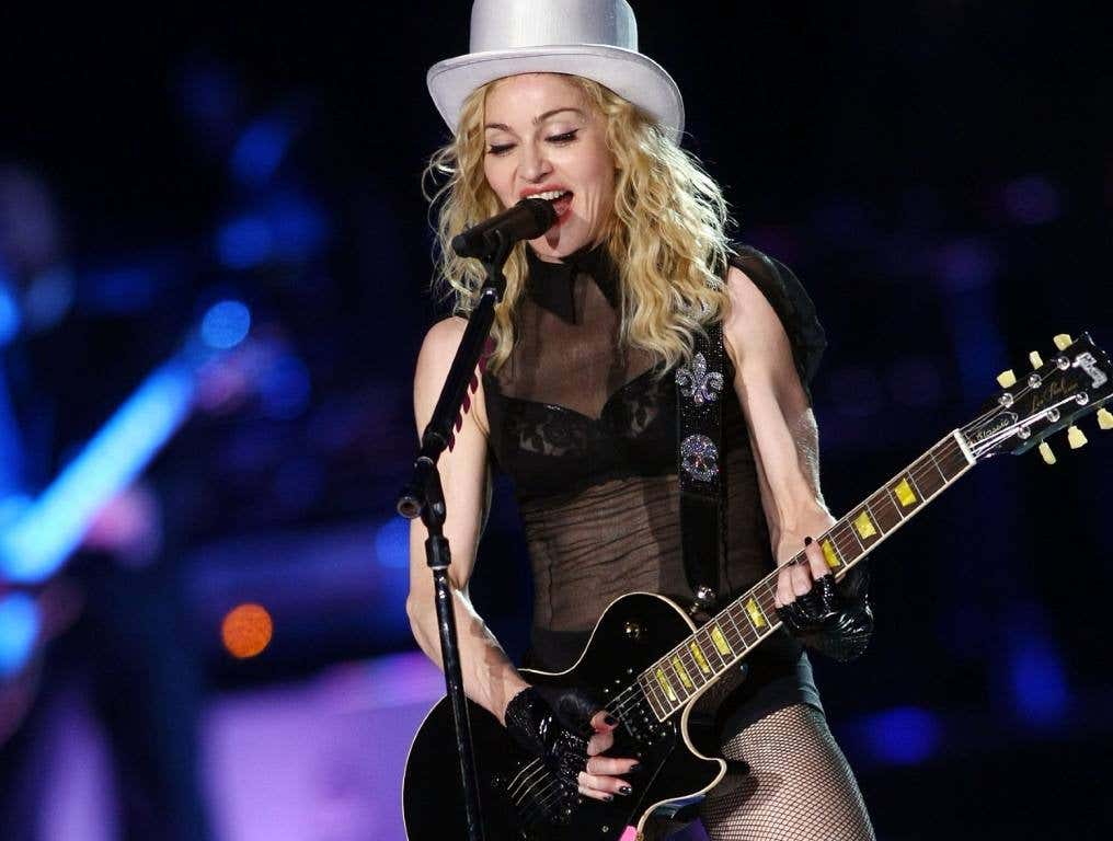 Madonna with a guitar in concert standing at the microphone