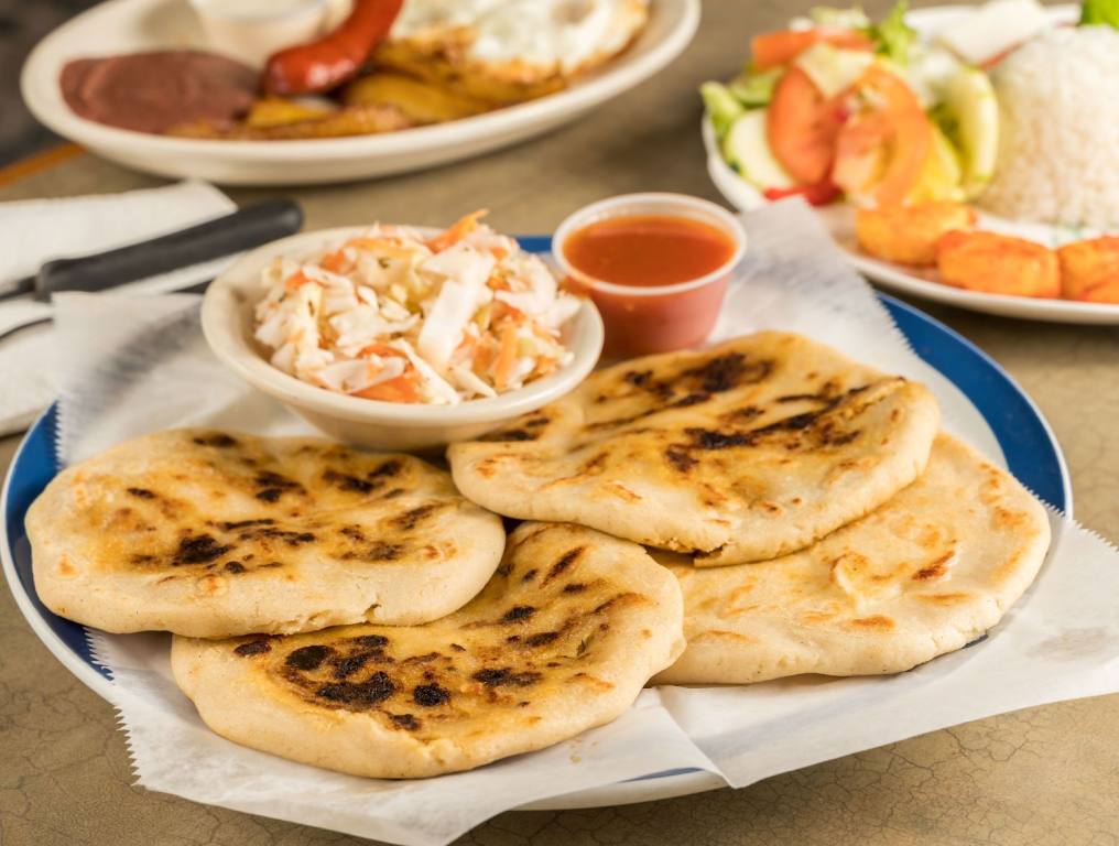 A dish of pupusas and others mexican food on the take out Mexican restaurant table