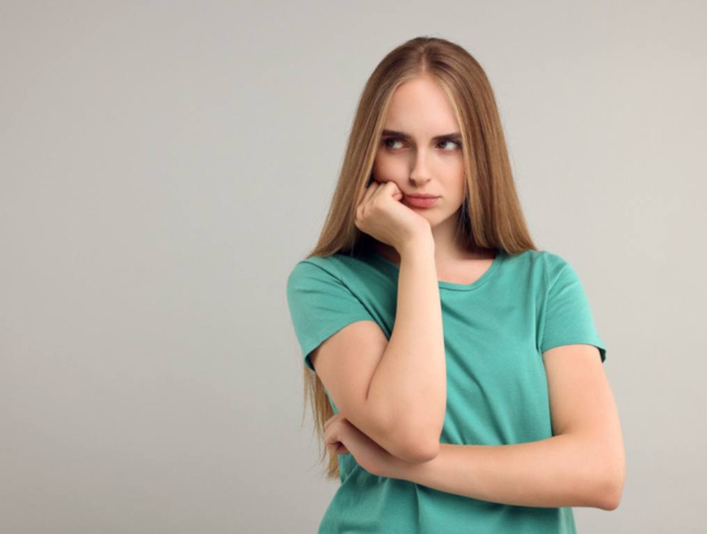 Resentful woman on grey background, space for text