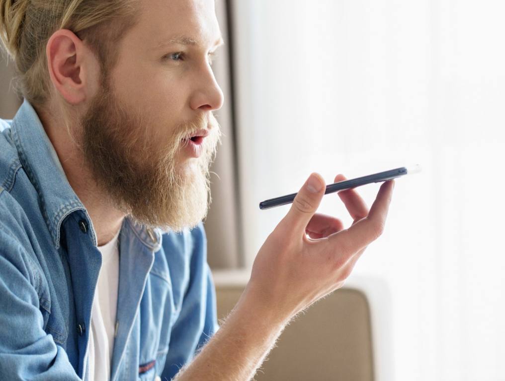 Guy with a beard talking into his cellphone through speakphone