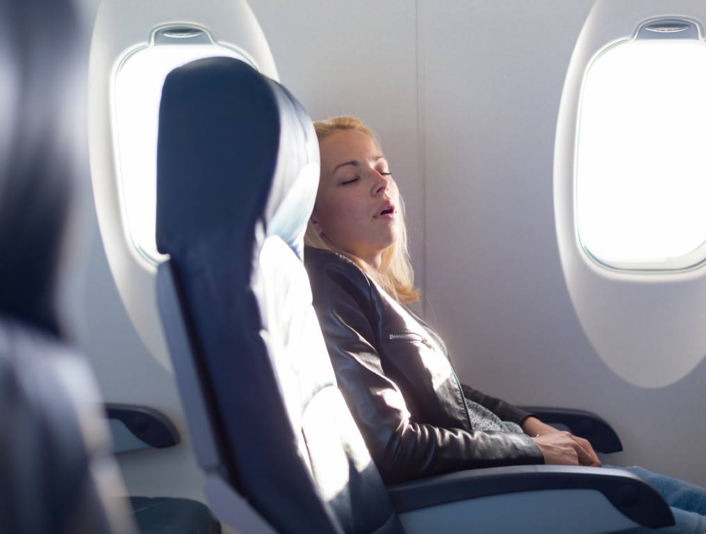 A passenger on a plane reclining in her seat.