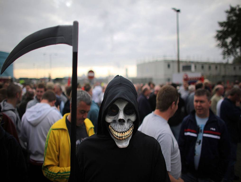 Grim Reaper with his cane blade, standing in front of a crowd of people.