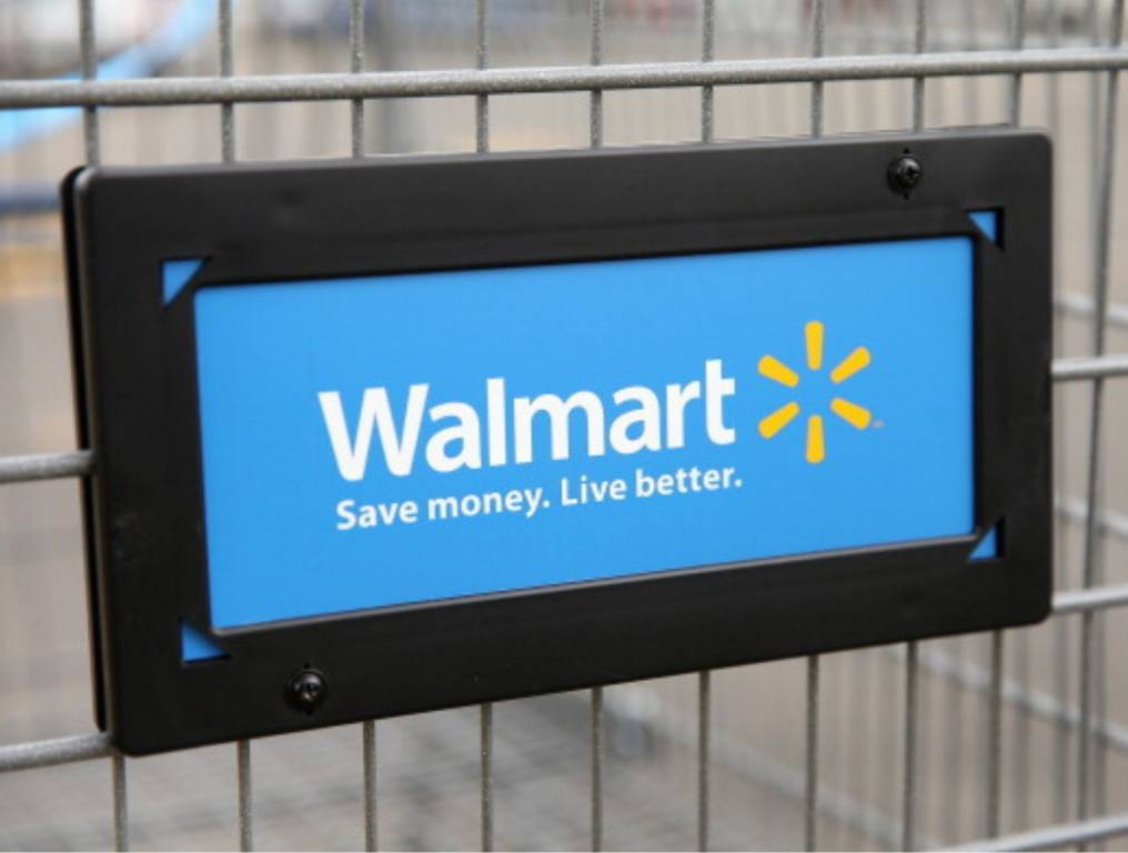 The Walmart logo is displayed on a shopping cart at a Walmart store