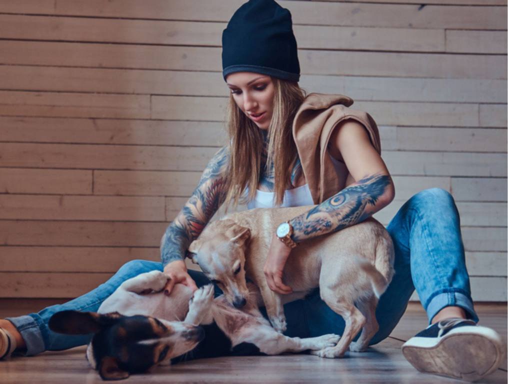 A stylish tattoed, tattoos blonde female in t-shirt and jeans with her dogs