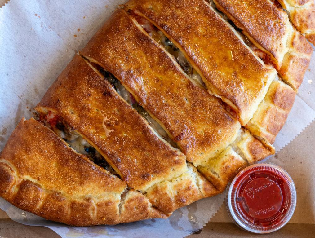 Best stromboli sitting next to a marinara cup.