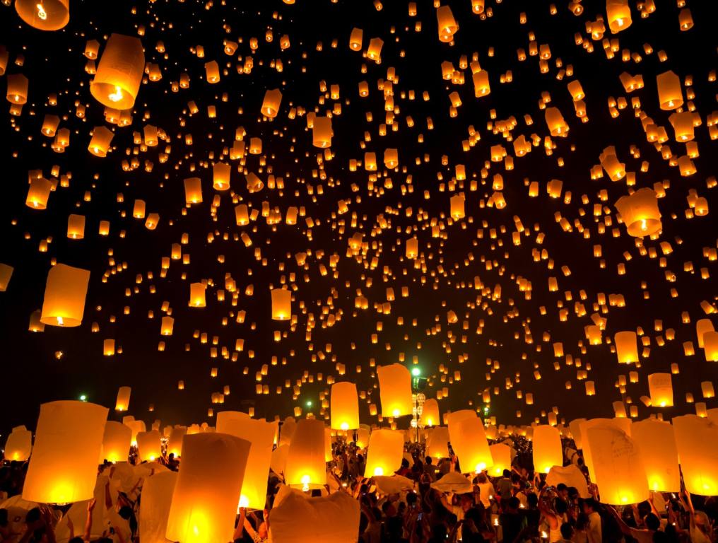 Photo of a sky lantern festival similar to The Lights Fest in Littlefield, Arizona, Saturday, May 11, 2024. Thousand of illuminated sky lanterns are released in the night sky by festival goers on the ground. Orange candle-lit paper sky lanterns against a dark, black sky.