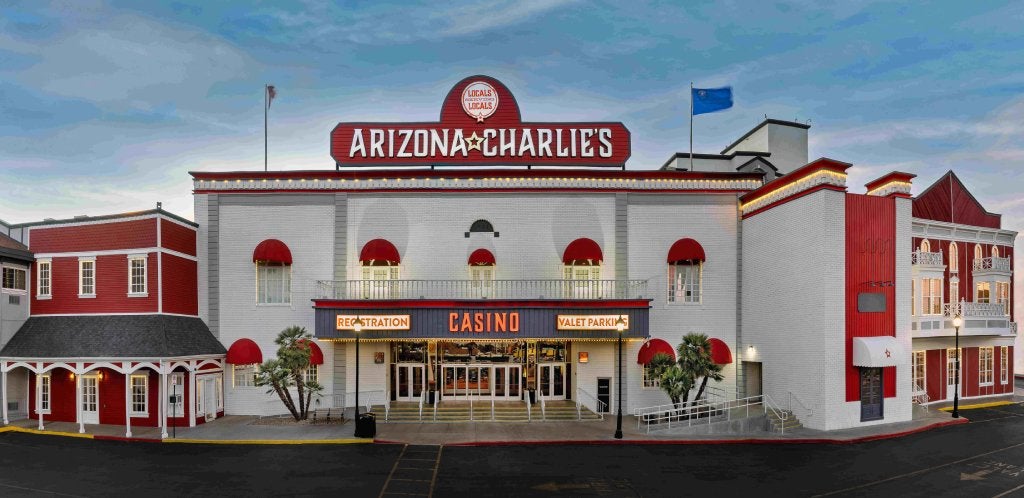 The exterior facade of Arizona Charlie's Decatur location in Las Vegas. The building is white with red trim and red and white signage.