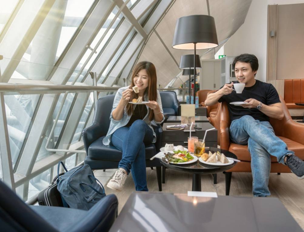 Asian couple sitting and eatting inn airport lounge when waiting the flight at modern international airport, travel and transportation concept