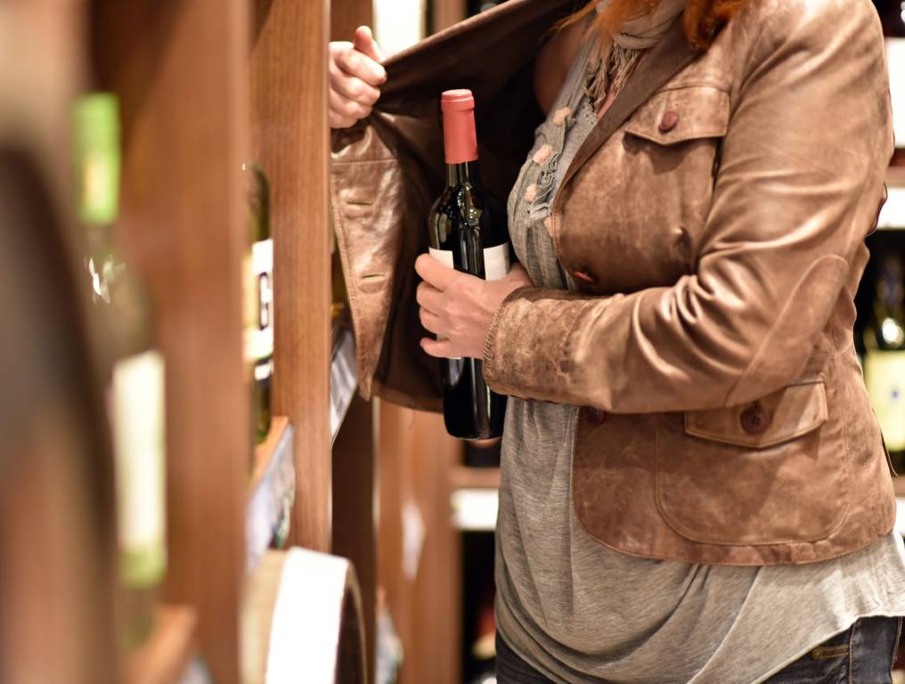 A woman trying to steal a bottle of wine in her jacket!