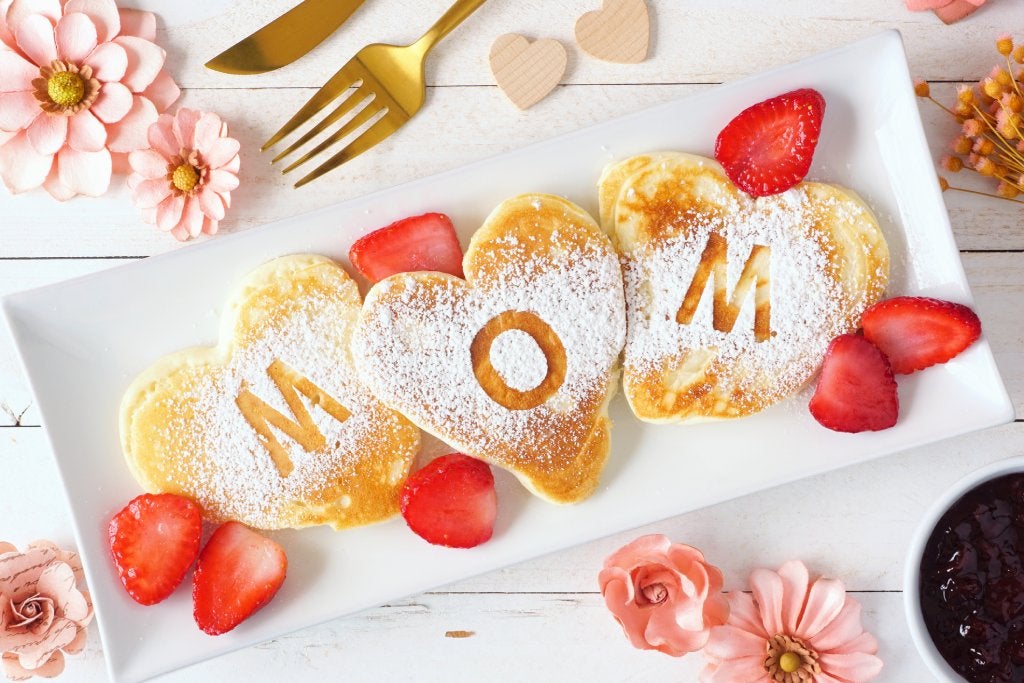 Heart shaped pancakes with MOM letters. Mothers Day breakfast concept. Top view table scene with a white wood background. Mother's Day In Vegas concept.