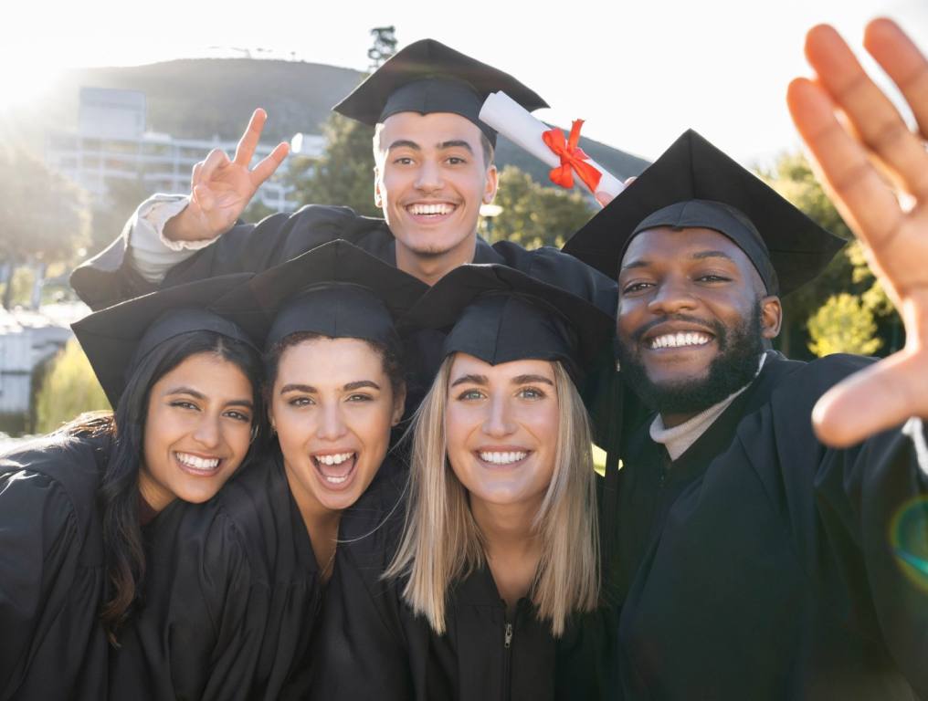 A group of ethnically diverse Clark County graduates take a selfie in their caps and gowns.