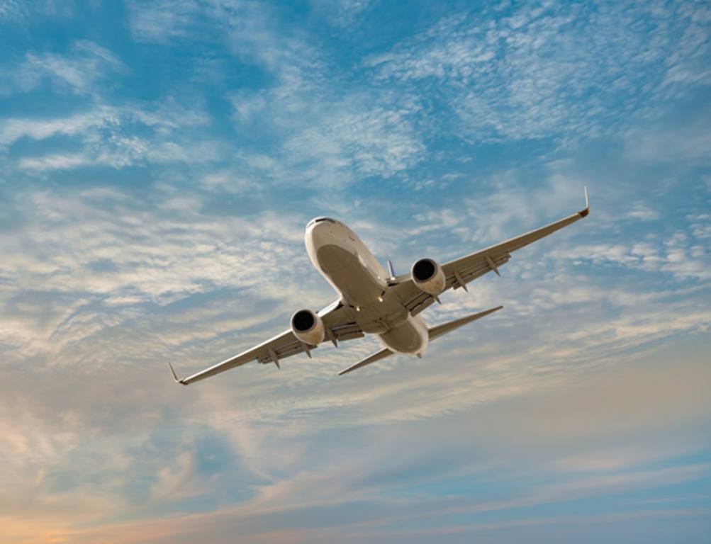 Airplane flying over tropical sea at sunset , travel concept