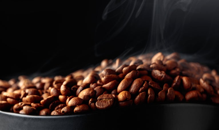 Steaming coffee beans on a black background. The Human Bean coffee shop.