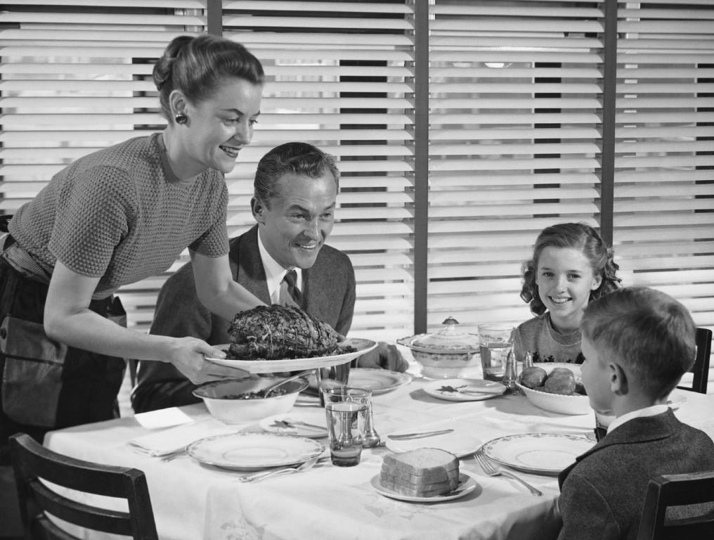 A mom serving dinner to her husband and kids.