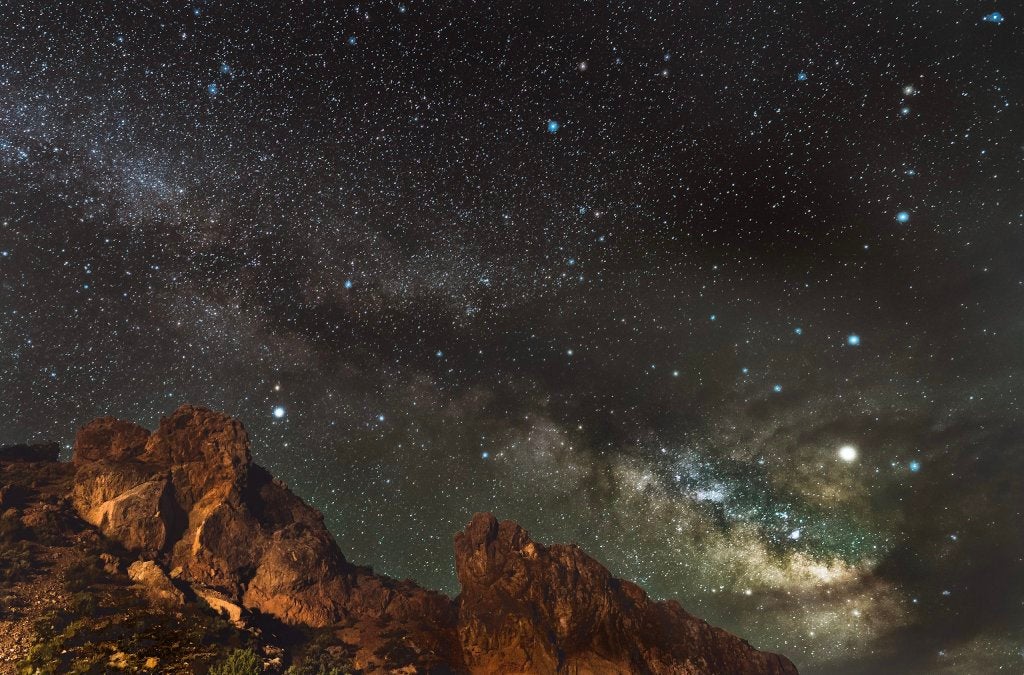 The night sky full of stars in the Milky Way over a mountain range.