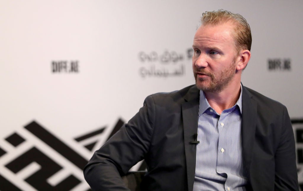 Morgan Spurlock with a blue button down shirt and a brown blazer.