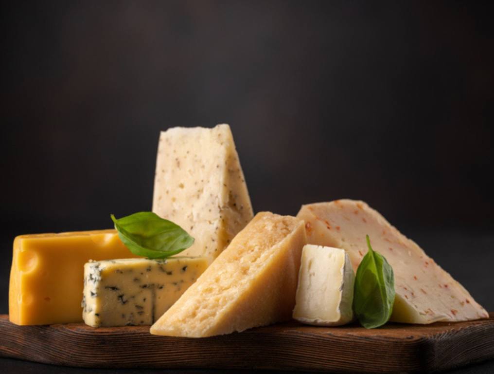 All kinds of cheeses on a wooden board.