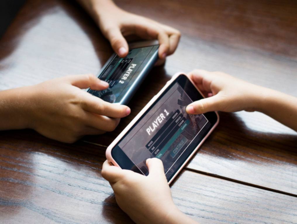 Playable games on mobile phone. Little boy playing a mobile game against his sister .