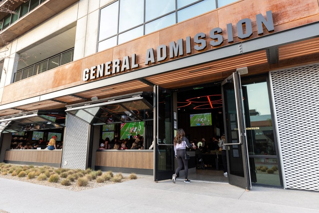 The facade of a sports bar shows "General Admission" lettering above an open wall with a sports bar inside.