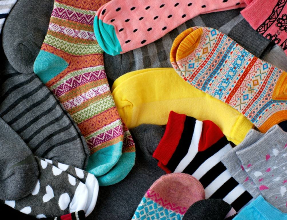 Many colorful socks form a textural background. Socks of different types and sizes.