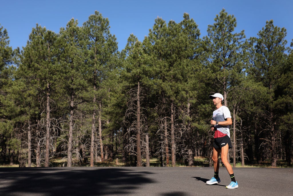 A man outdoors on a tree-lined path getting ready to run on a sunny day wearing the best running shoes for dads