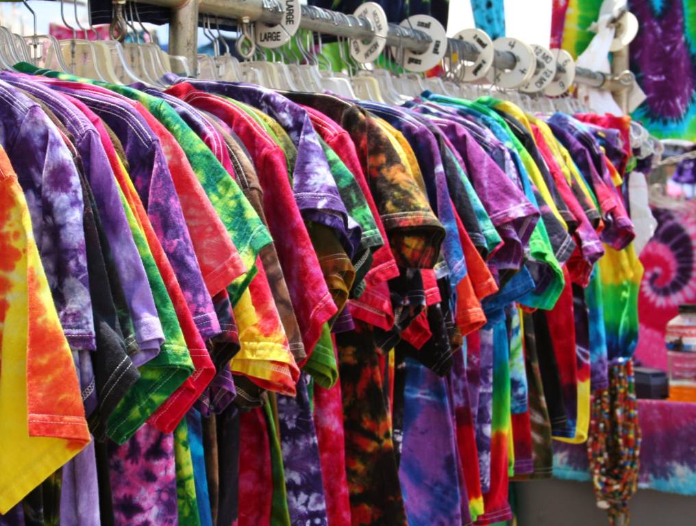 A row of die-dyed t-shirts on a rack ready for sale. Concept: Shakedown Street