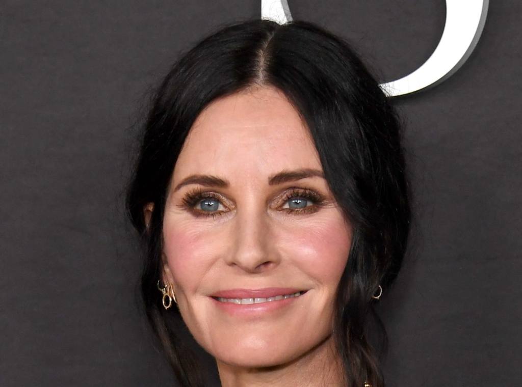 Courteney Cox attends the Premiere of STARZ "Shining Vale" at TCL Chinese Theatre smiling wearing a black top with stacked gold necklaces. Courteney Cox Recreates Bruce Springsteen's 'Dancing In The Dark' Video.