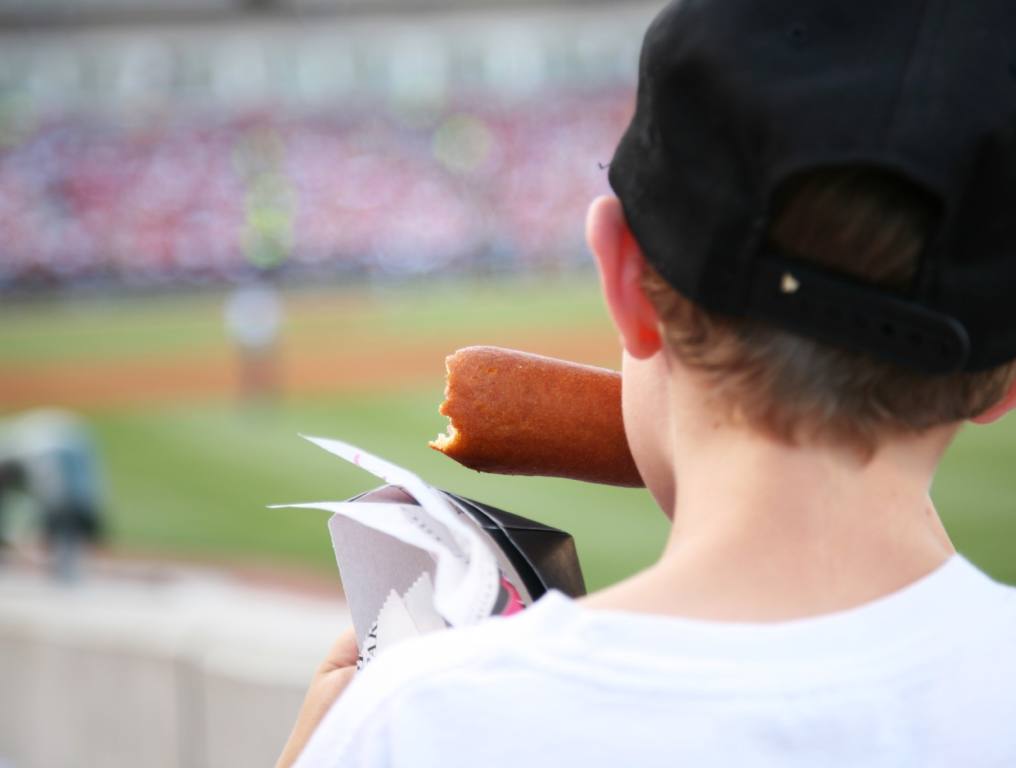 A kid eating a hot dog at a ballpark possibly in Nevada.