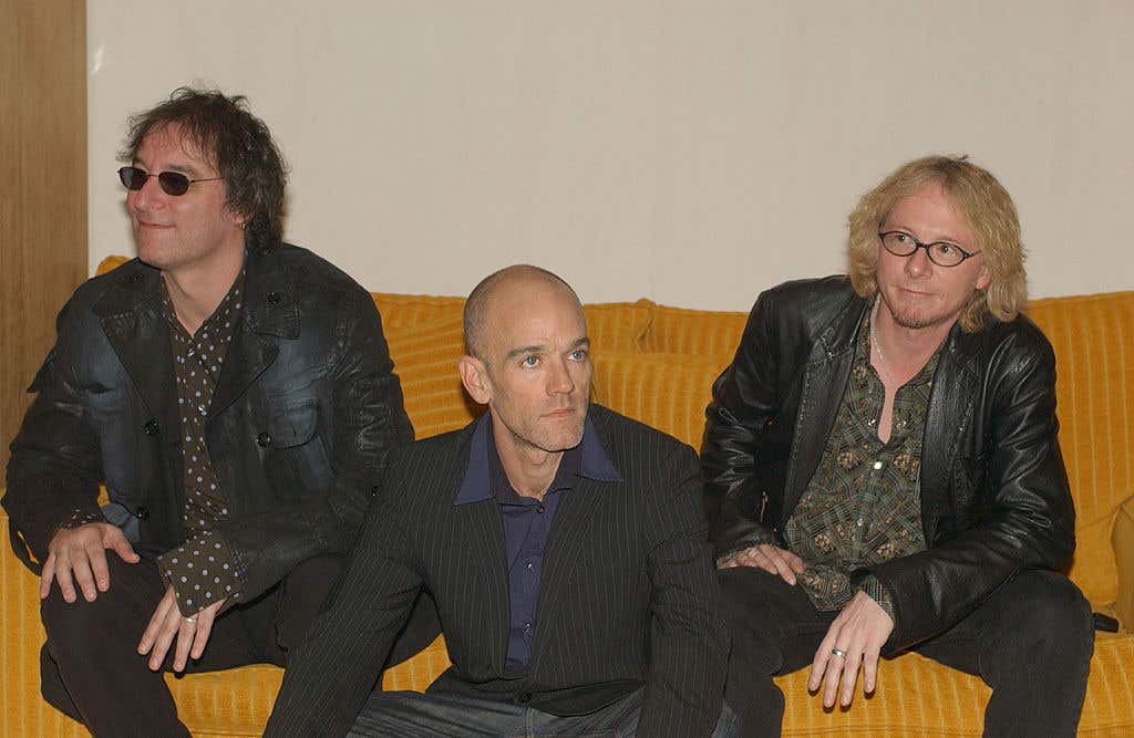 Peter Buck, Michael Stipe and Mike Mills of R.E.M. sitting on a couch