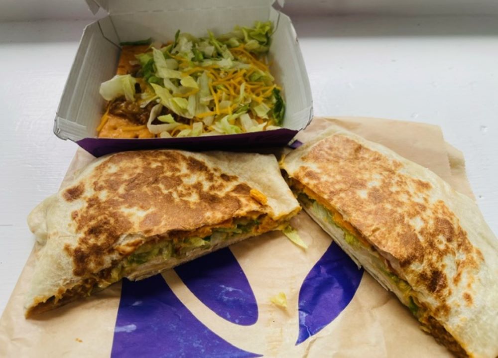 The Taco Bell Cheez-it crunchwrap and tostado in a box on a white table