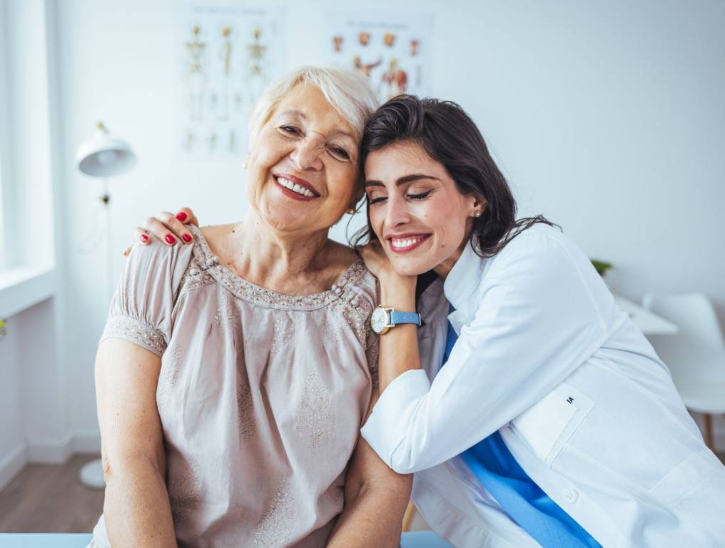 Doctor and elderly woman hugging.