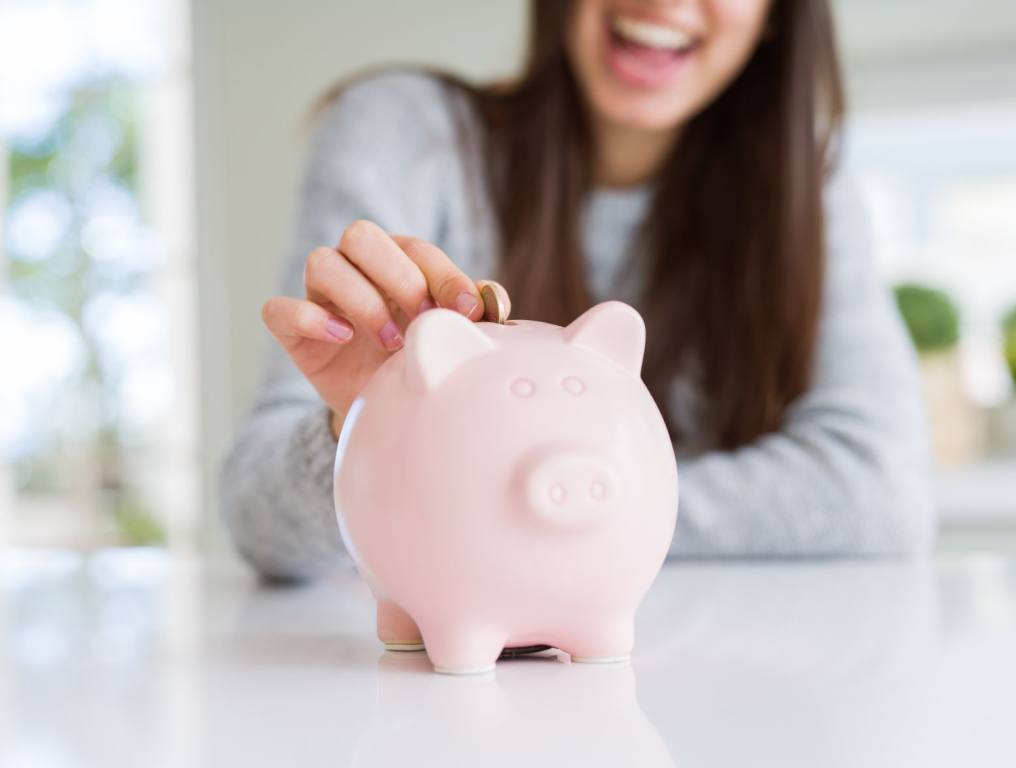 Woman putting money in piggy bank.