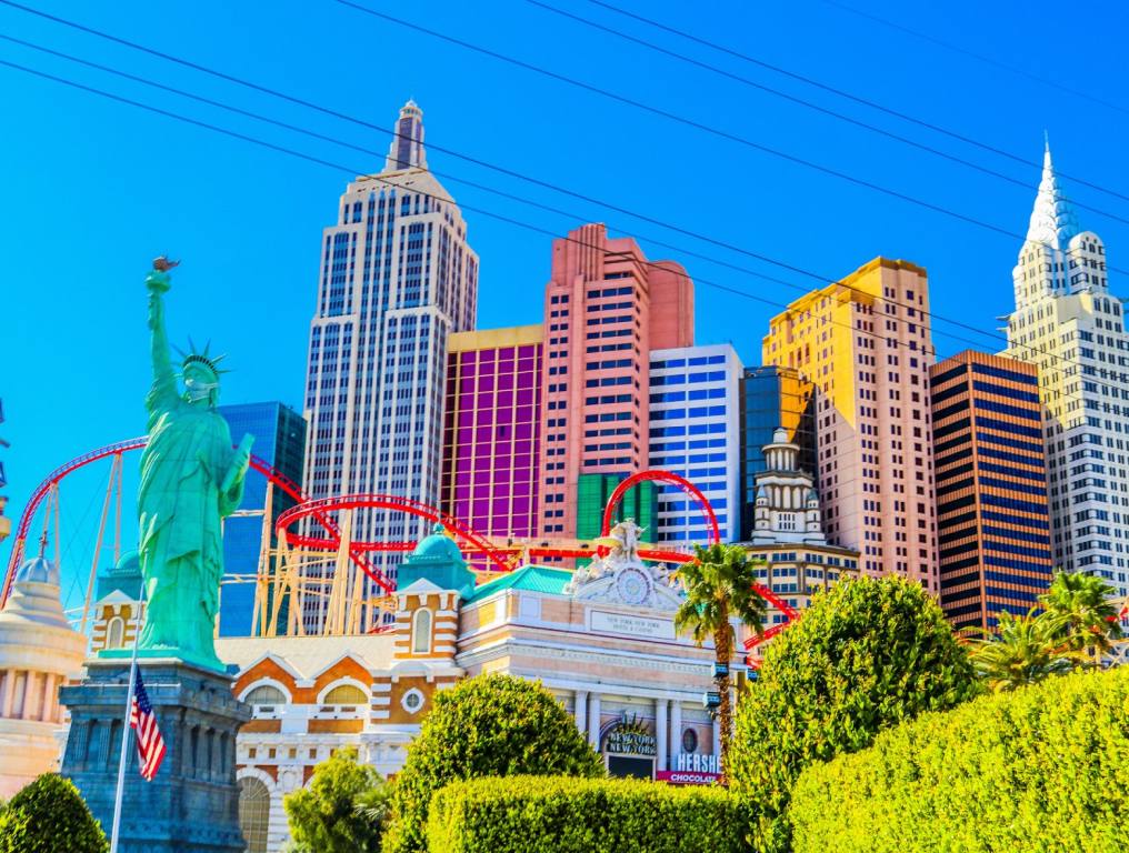 A close-up photo of the New York New York on the Las Vegas Strip shows the Statue of Liberty replica and coloful skyscrapers. Concept: Landmarks people photograph