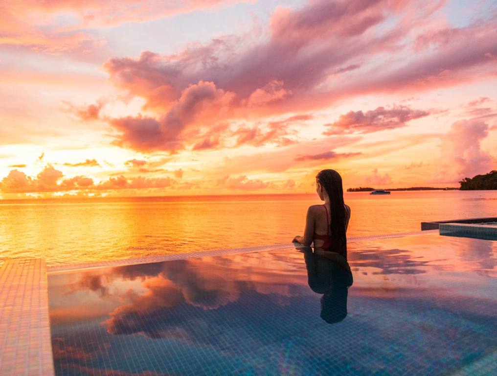 A woman in Tahiti watching the sunset. Watching the surfing competition in Tahiti makes me want to go to Tahiti, so I decided to do some research into what it takes to get there and what to know before you go.