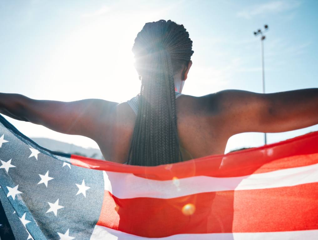 An athlete at the Olympic games holding up an American flag.