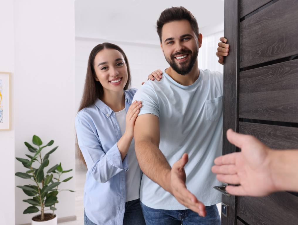 A young couple opening their door to meet their new neighbors.