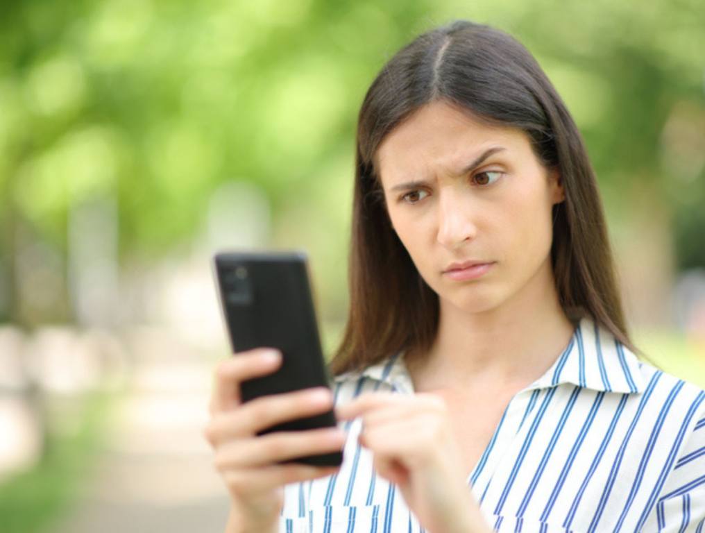 Woman reading suspicious message on phone