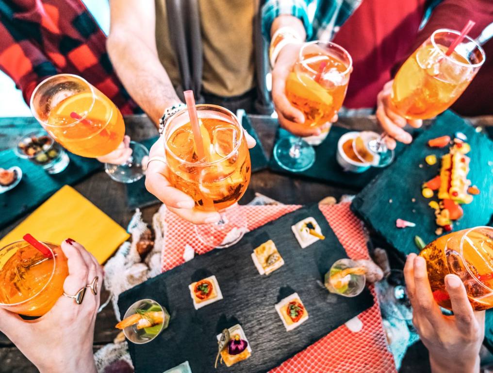 People cheering with cocktails that are mostly Aperol Spritz cocktails