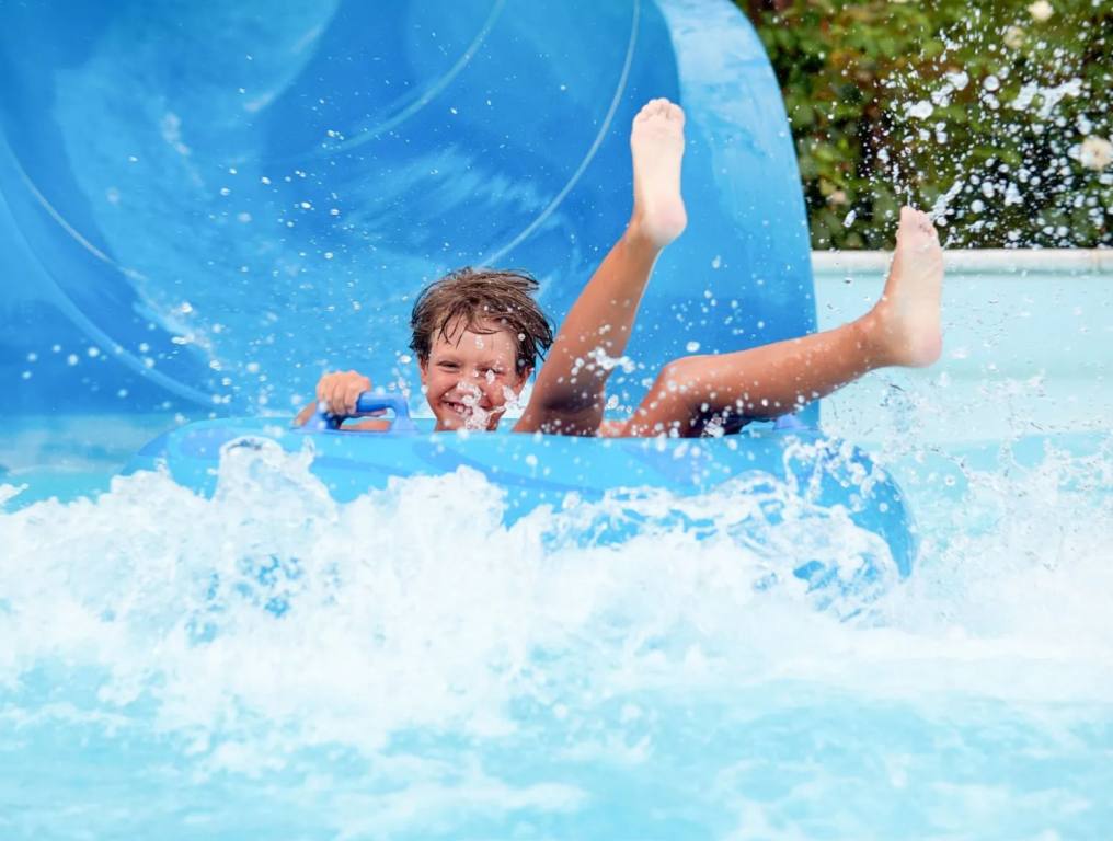 young boy going down water slide on tube at water park